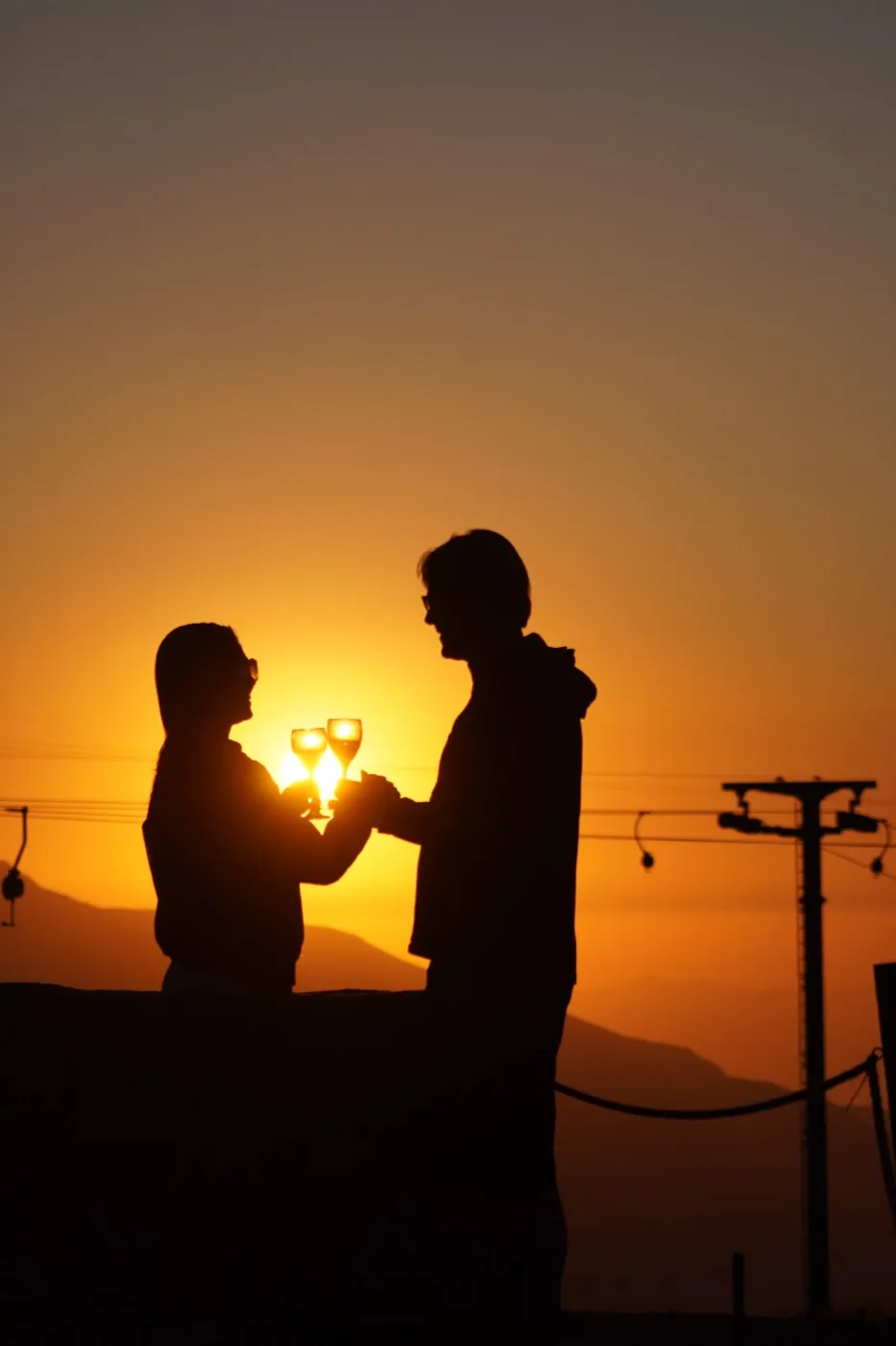 Silhueta de um casal brindando ao pôr do sol
